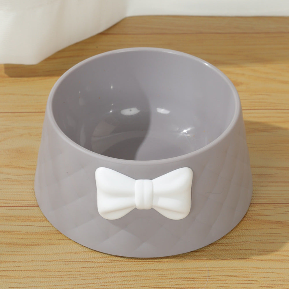 Pink pet food dish with a bow design, filled with dry kibble

