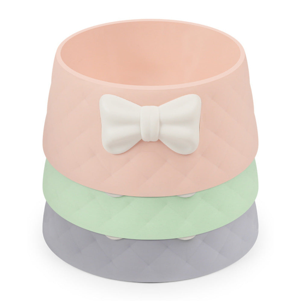 Pink pet food dish with a bow design, filled with dry kibble

